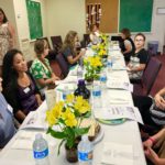 People seated around long table with flowers