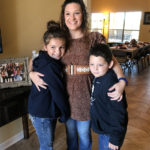 Smiling woman hugging two children indoors
