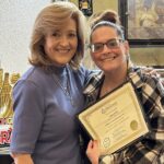 Two women smiling, holding certificate