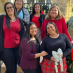 Six women posing outdoors in red and black