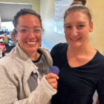 Two smiling women holding blue token